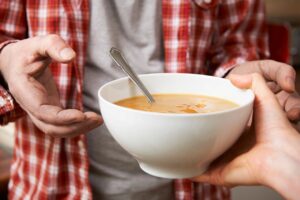 a person giving another person a bowl of soup